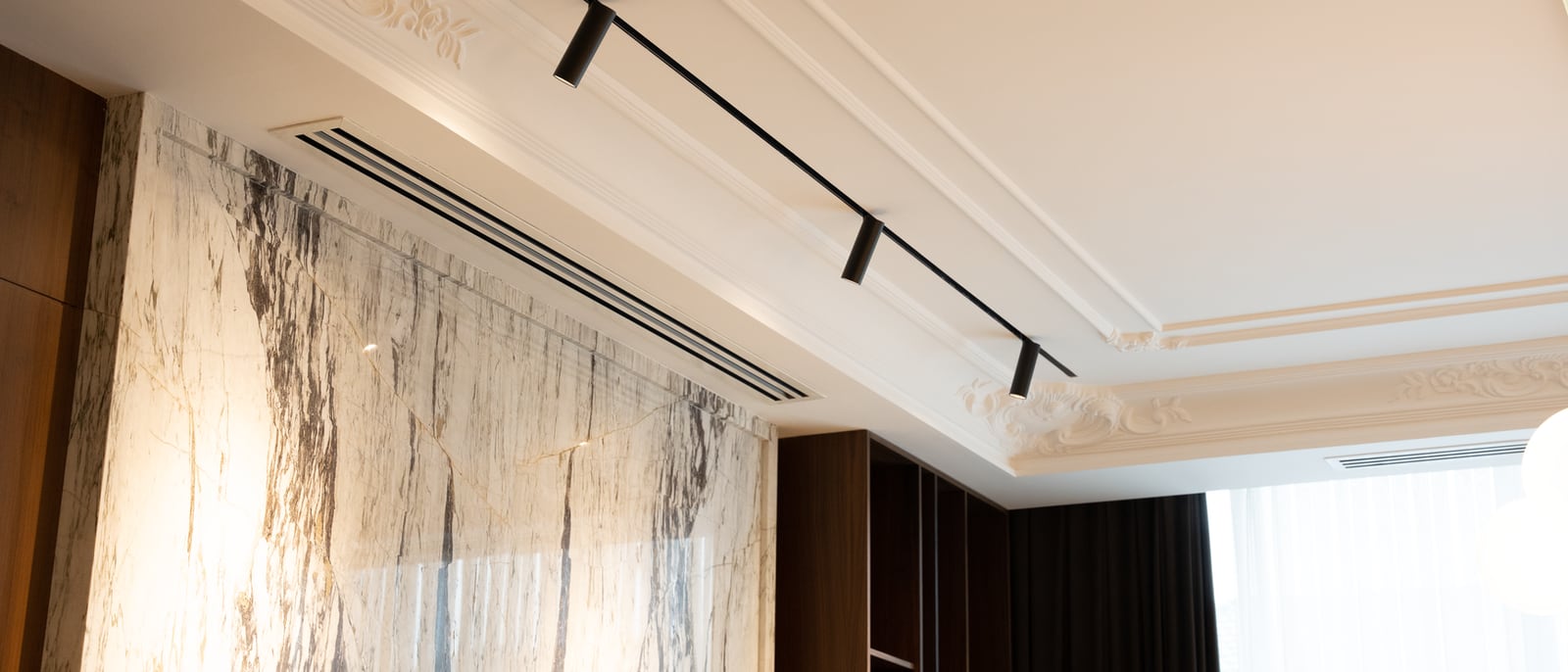 Rail de spots orientables installé au plafond mouluré d'un séjour
